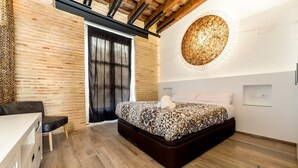 A modern bedroom with a large bed, a wooden floor, a black bench, and a unique wall light. - CENTER-Luxurious 1BR, 1BA-Terrace, WI-FI, A/C (Valencia)