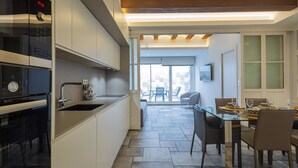 Een moderne keuken met een ingebouwde oven, een spoelbak en een eethoek met een glazen tafel en stoelen.
