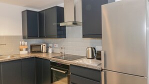 Eine moderne Küche mit dunklen Schränken, Edelstahlgeräten und einem eingebauten Backofen.