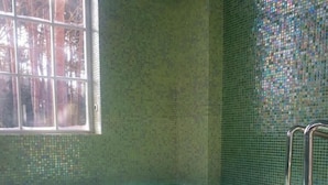 Una bañera de hidromasaje con interior de azulejos, una ventana y una escalera metálica.