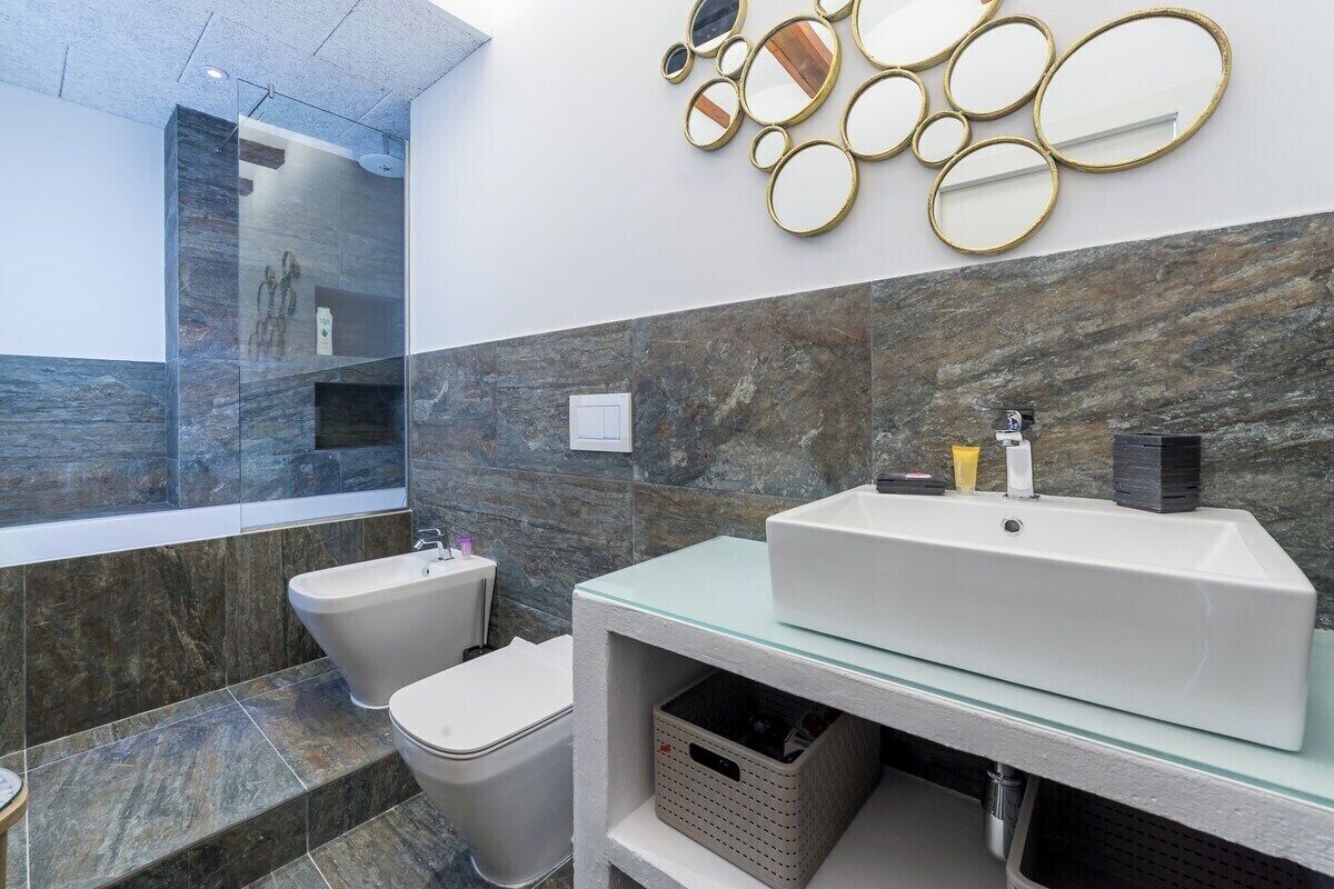 Un baño moderno con ducha de vidrio, una bañera independiente y un tocador con un espejo grande.