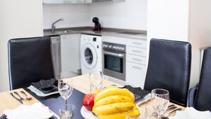 Ein Esstisch mit einer Banane, einem Apfel und Weingläsern, in einer modernen Küche mit Waschmaschine und Mikrowelle im Hintergrund.
