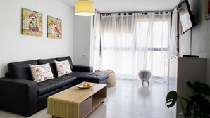 Ein modernes Wohnzimmer mit einem schwarzen Sofa, einem Holztisch und einem großen Fenster mit durchsichtigen Vorhängen.