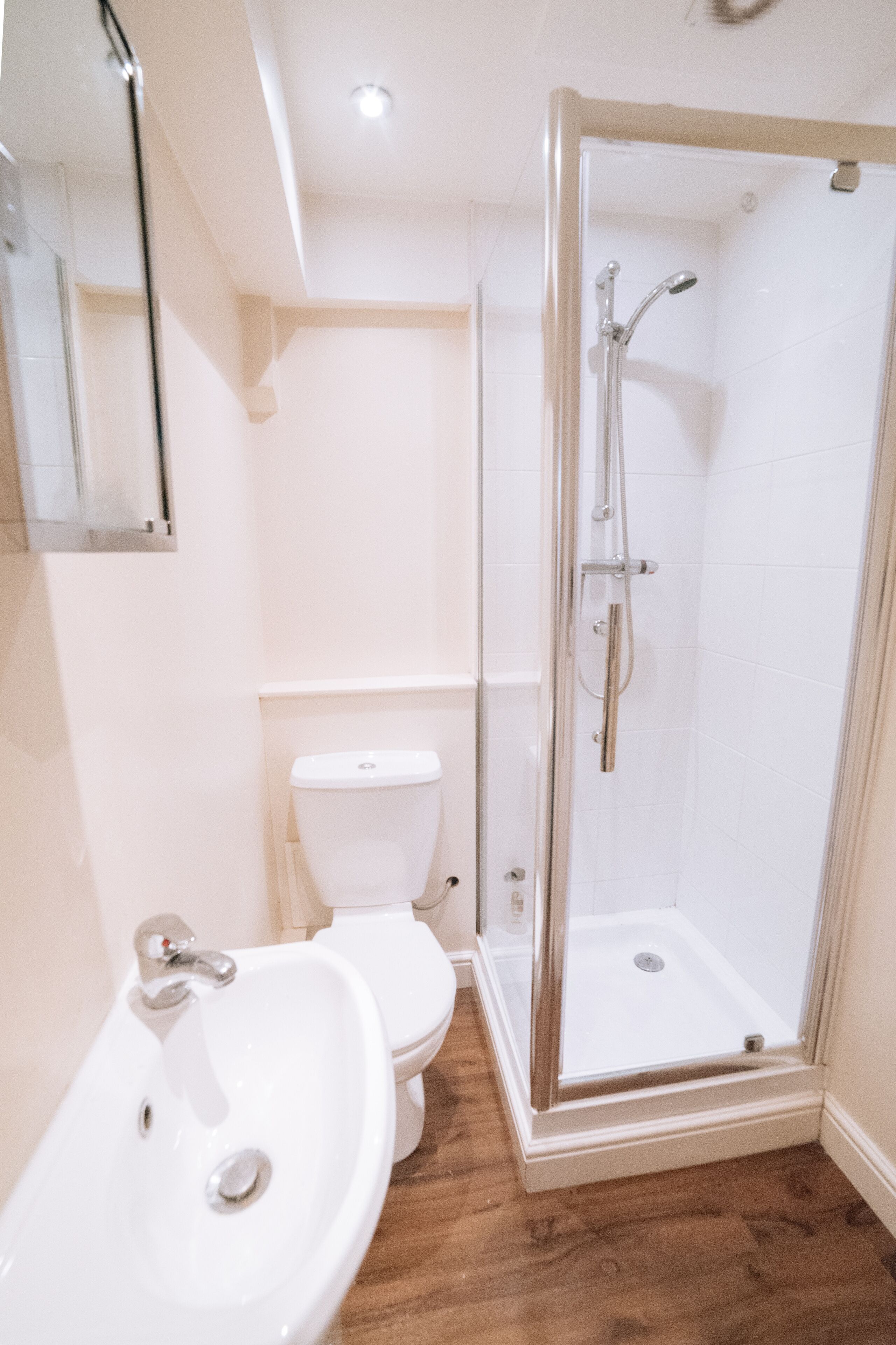 Ein Badezimmer mit Toilette, Waschbecken und einer gläsernen Duschkabine.