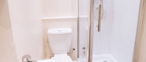 Ein Badezimmer mit Toilette, Waschbecken und einer gläsernen Duschkabine.