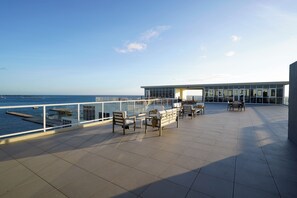 A rooftop terrace with seating and a view of the sea.