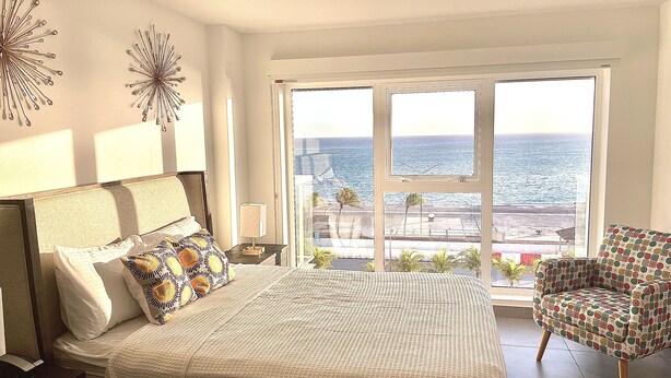 Une chambre avec un grand lit, une chaise et une vue sur la mer.