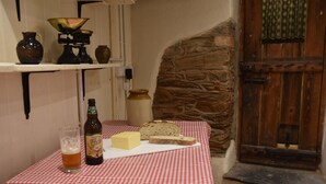 Une table recouverte d’une nappe à carreaux, une bouteille de bière, un verre de bière, un morceau de fromage et une miche de pain.