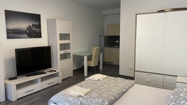 A modern bedroom with a bed, a TV, a desk, and a wardrobe. - Pension Neon (Mannheim)