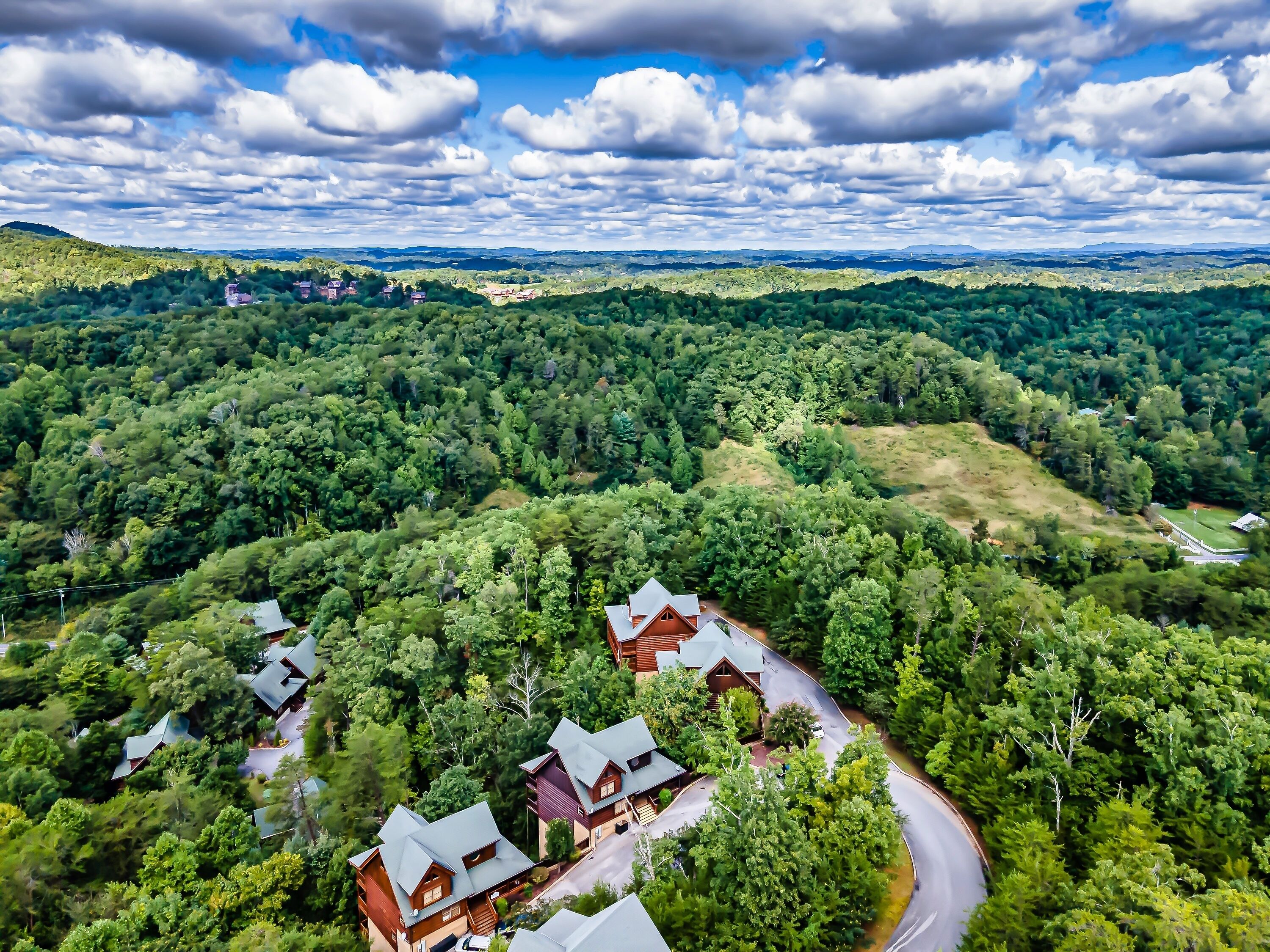 A remote, forested area with several cabins and a winding road.