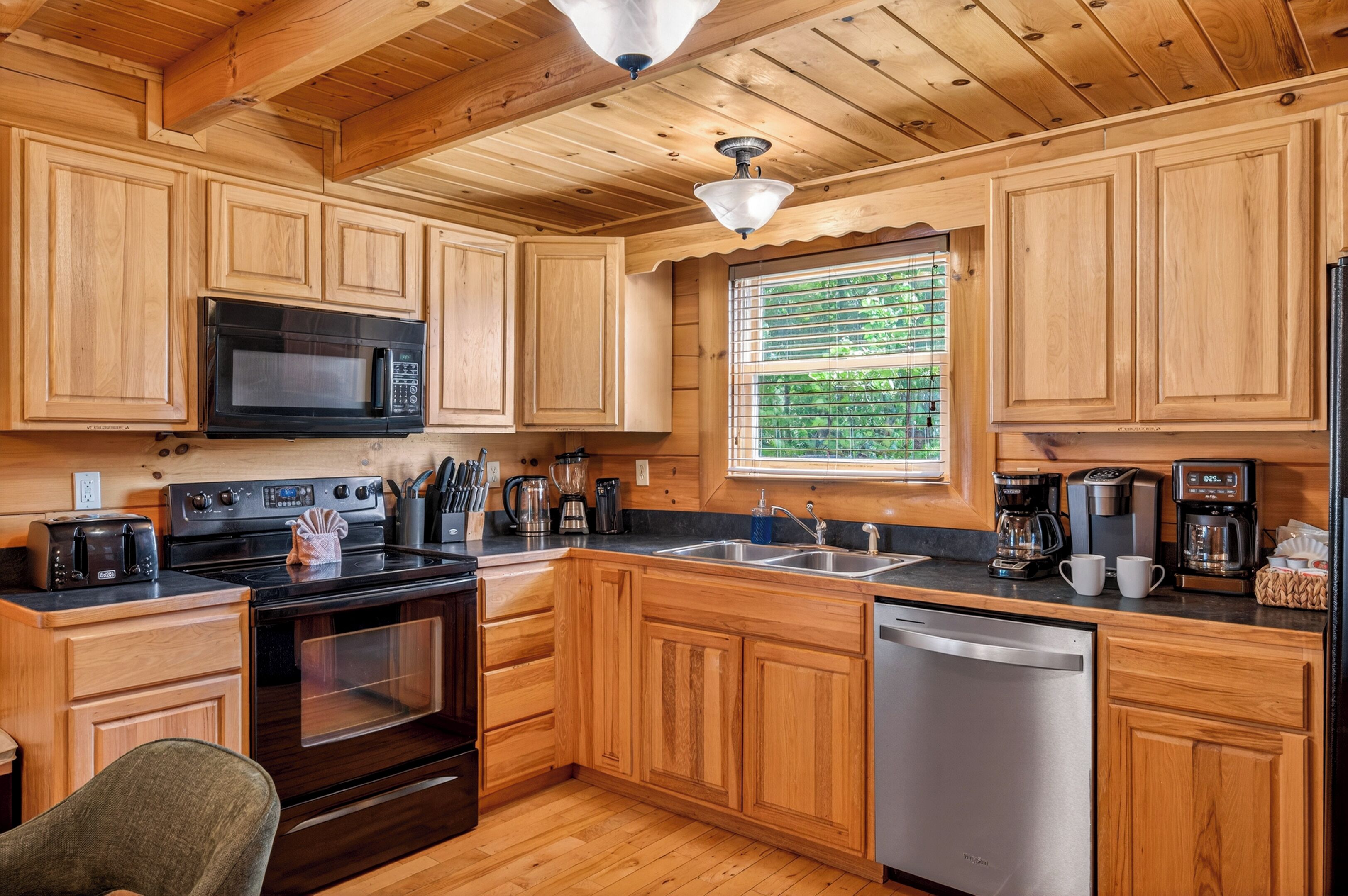 A kitchen with wooden cabinets, a microwave, stove, sink, and dishwasher.