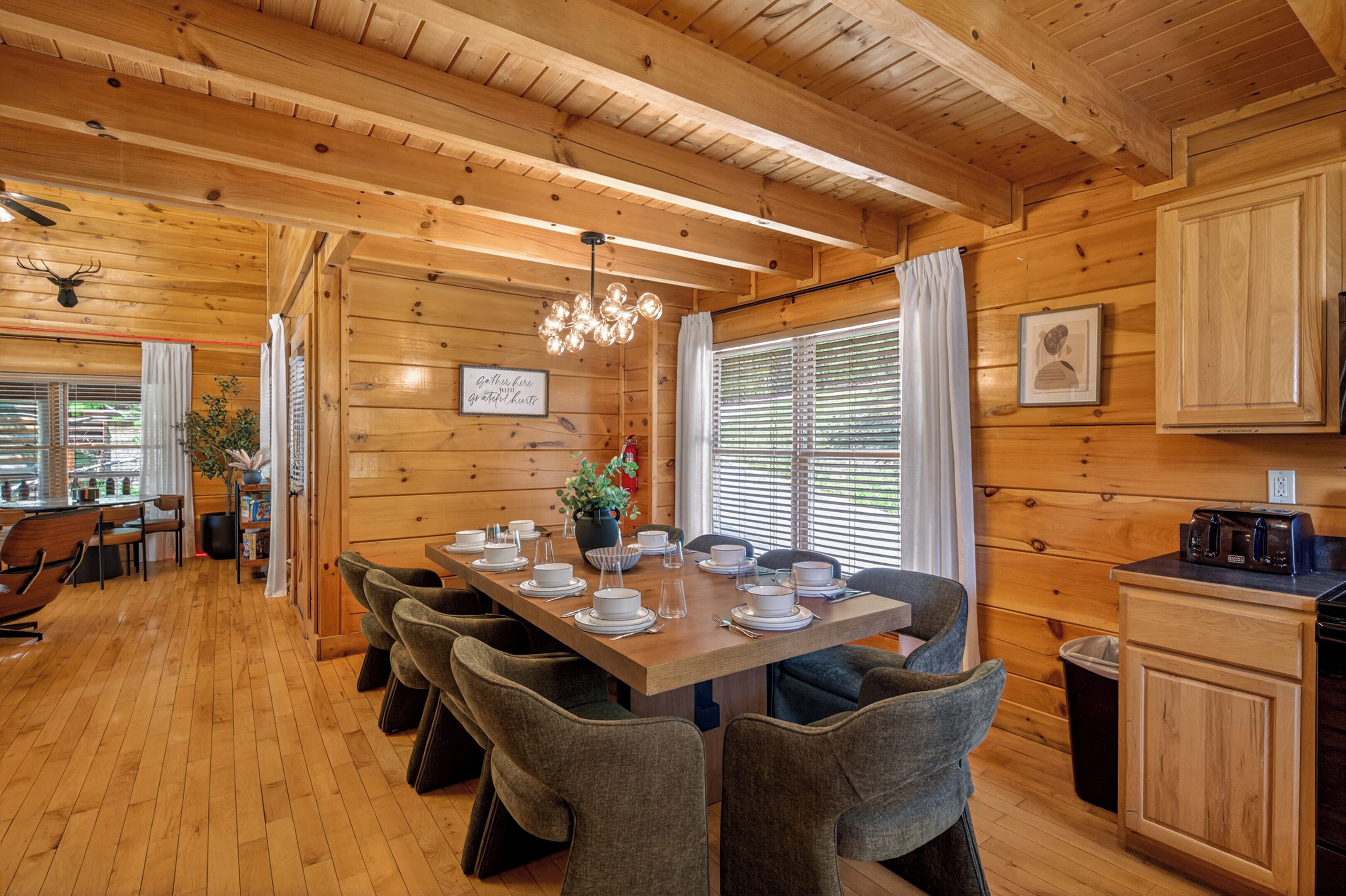 A wooden interior with a dining table set for four, a kitchen area, and a ceiling fan.