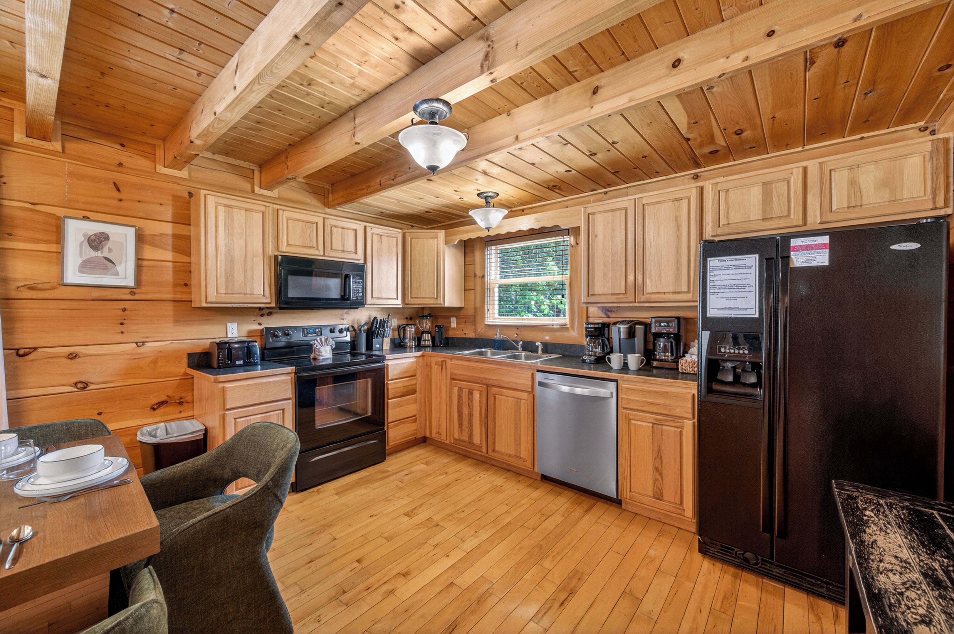 A wooden cabin-style kitchen with a microwave, stove, dishwasher, and refrigerator.