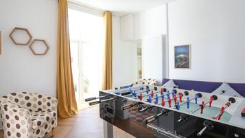 A room with a foosball table, a polka dot chair, and a view through a large window.