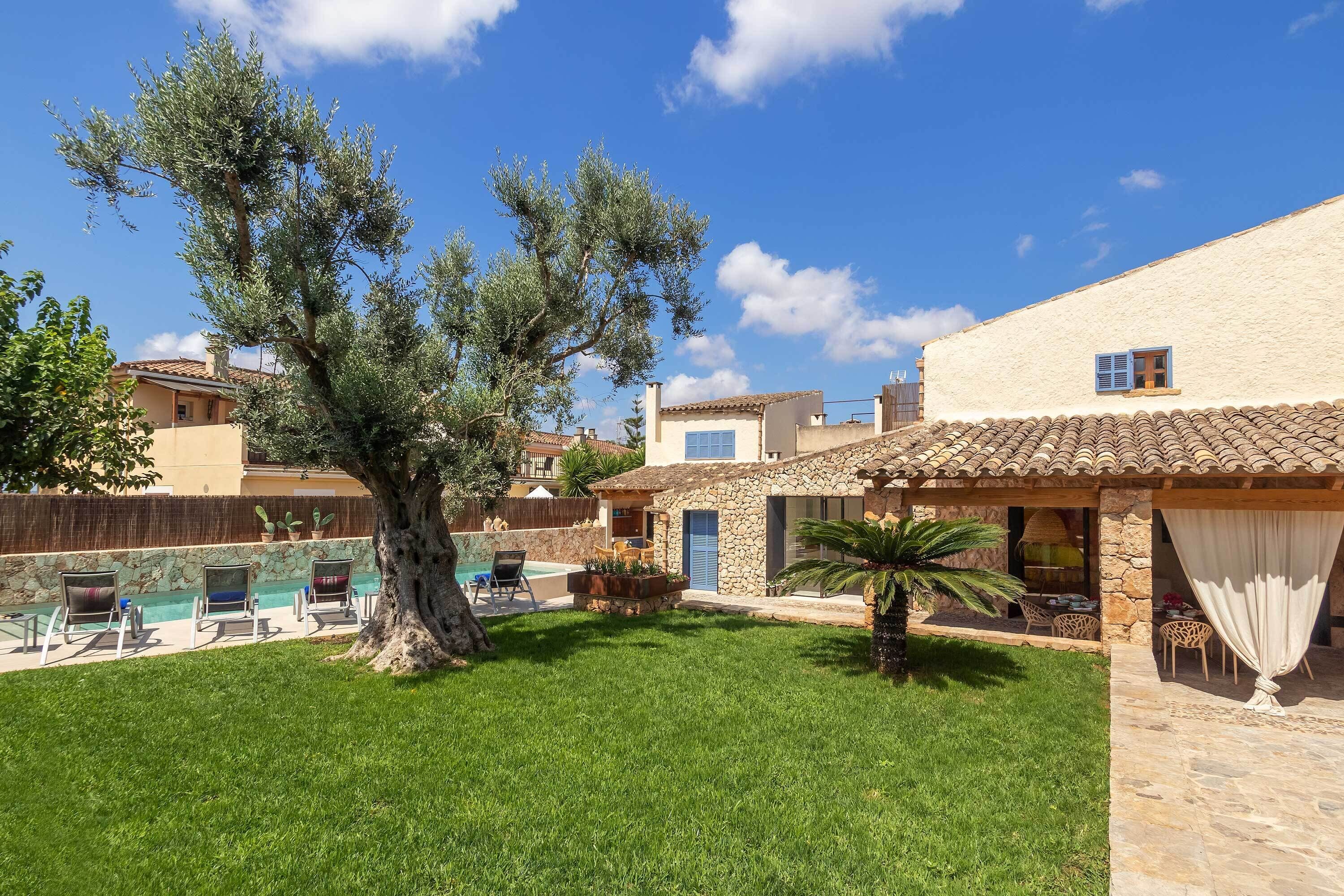 A villa with a swimming pool, outdoor seating, and a large tree.