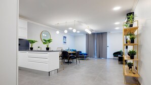 A modern living room with a dining area, a kitchen, and a built-in bookshelf. - Art Deco Luxury Apartment, Central Location (Sliema)