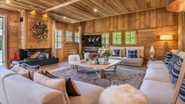 Ein gemütliches Blockhaus-Interieur mit Kamin, Holzwänden und einer bequemen Sitzecke.