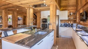 Eine moderne Küche mit Holzelementen, Edelstahlgeräten und einer zentralen Kochinsel mit Spüle.