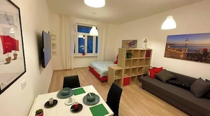 A compact living space with a dining area, a sofa, a bed, and a window with curtains. - NEVERIN 🍾3 Luxury apartments (Trieste)
