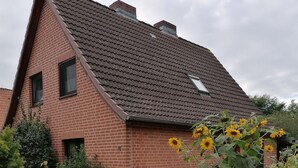 A brick house with a sloped roof and a garden with sunflowers. - Vacation apartment on the Elbe-Lübeck Canal. Ideal for cycling tours. (23919 Berkenthin)