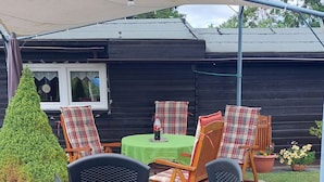 A patio area with a table and chairs, a small tree, and a house in the background. - Vacation apartment on the Elbe-Lübeck Canal. Ideal for cycling tours. (23919 Berkenthin)