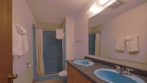 Une salle de bain avec deux lavabos, des toilettes et une douche.