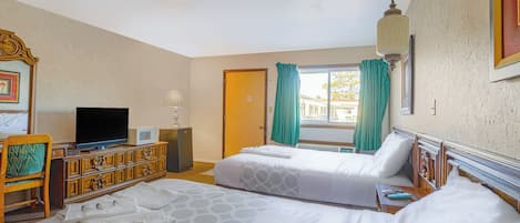 Une chambre d’hôtel avec deux lits, une télévision, une commode et une fenêtre avec des rideaux.
