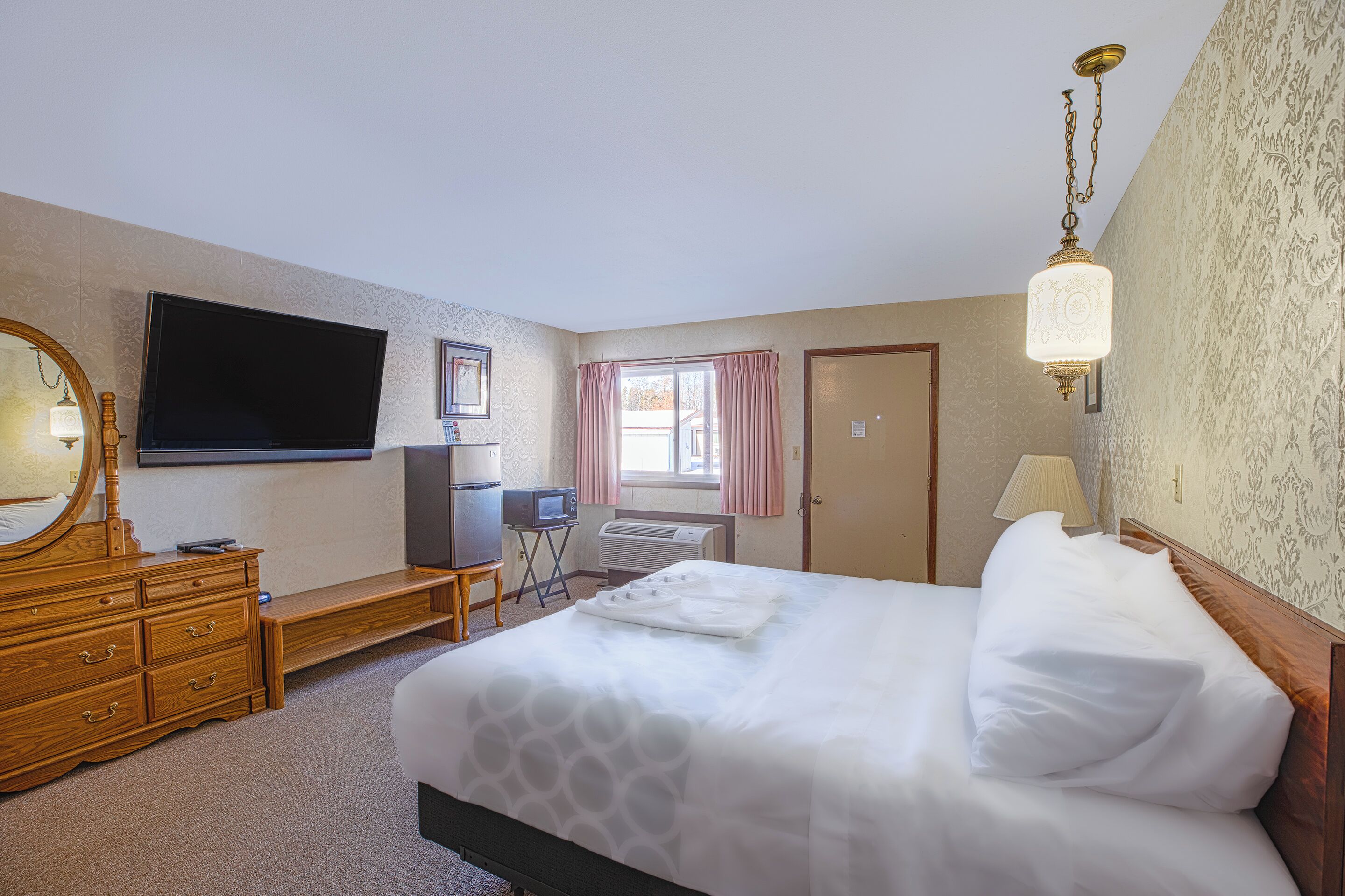 Une chambre d’hôtel bien aménagée, avec un grand lit, une télévision, une commode et un bureau équipé d’un ordinateur.