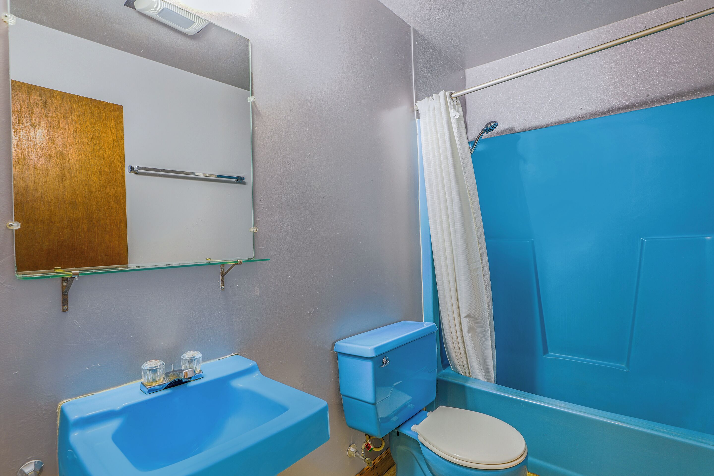 A bathroom with a blue sink, toilet, and bathtub.