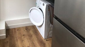 A compact kitchen with a washing machine, a refrigerator, and a microwave. - Lovely 4-bed House in Anfield all En-suite, (Liverpool)