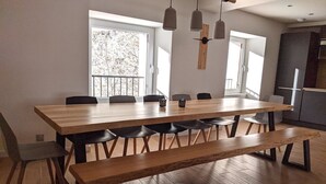 Uma sala de jantar moderna com mesa e cadeiras de madeira, um banco e iluminação pendente.