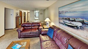 A living room with two leather sofas, a coffee table, a lamp, and a painting of boats on the wall. - 2 Bedroom Condo at Myrtle beach (Myrtle Beach)