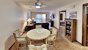 A dining area with a round table and four chairs, a ceiling fan, and a bookshelf with decorative items. - 2 Bedroom Condo at Myrtle beach (Myrtle Beach)