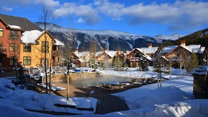 Une station de ski enneigée, avec des chalets, une piscine et des montagnes en toile de fond.