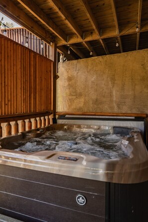 A hot tub with a wooden deck and a rustic ceiling. - Lux Lodge! Pool-Sauna-HotTub-Game-Pet Frndly (Sevierville)