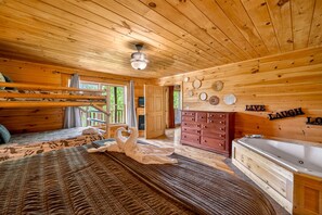 A wooden cabin interior with a bed, a dresser, a bathtub, and a wall with decorative plates. - Lux Lodge! Pool-Sauna-HotTub-Game-Pet Frndly (Sevierville)