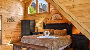 A cozy wooden cabin bedroom with a large bed, a bench, and a window with a view of houses. - Lux Lodge! Pool-Sauna-HotTub-Game-Pet Frndly (Sevierville)