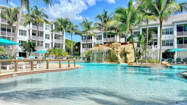 Ein Hotelpool mit klarem Wasser, Palmen und einem Wasserfall.