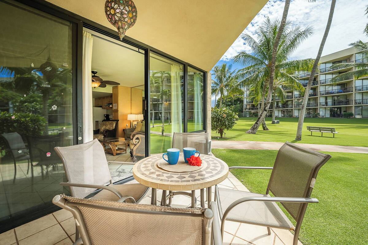 A patio with wicker chairs, a round table, and two blue cups.