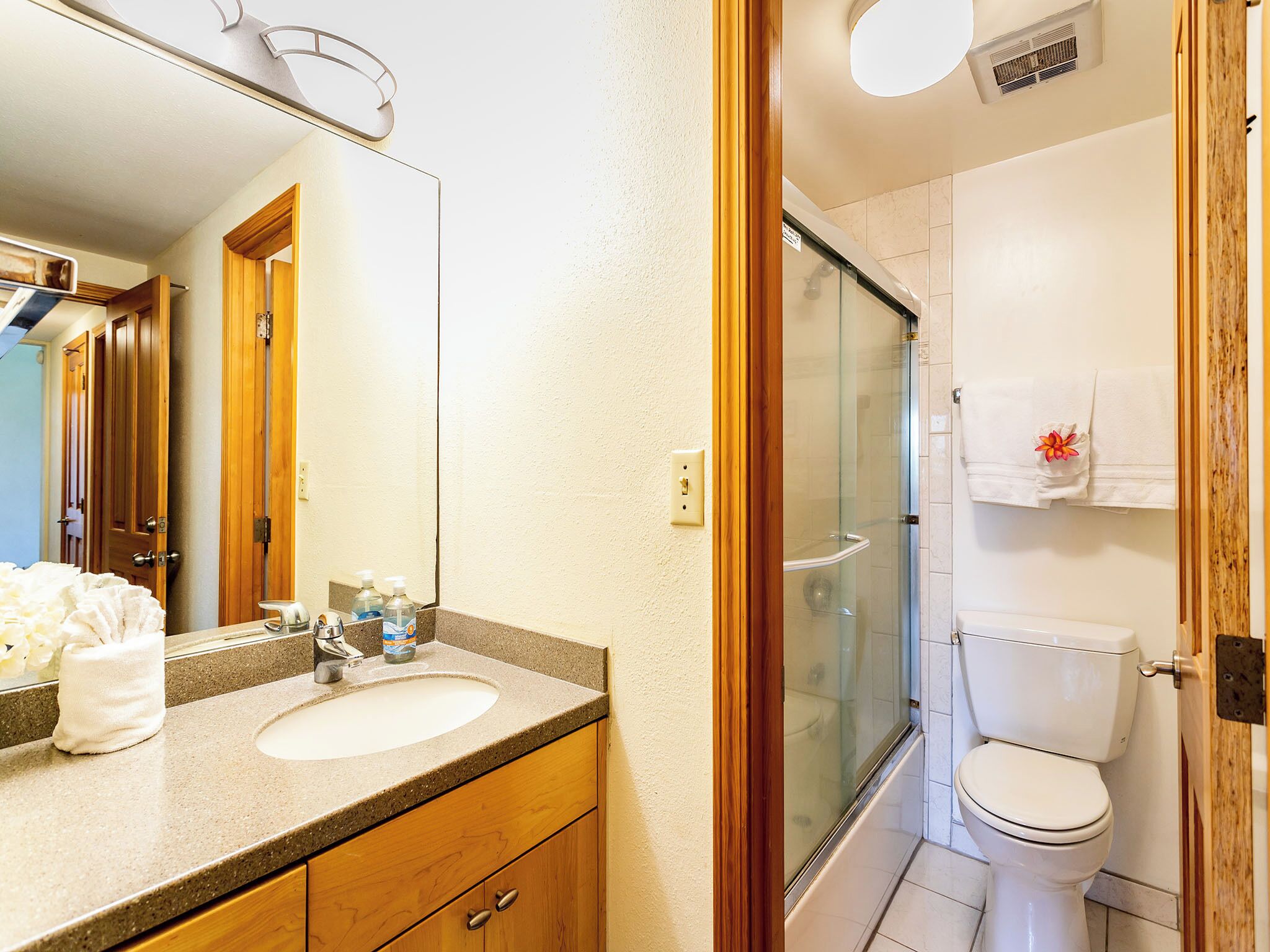 Un baño con lavamanos, espejo, inodoro y cabina de ducha de vidrio.