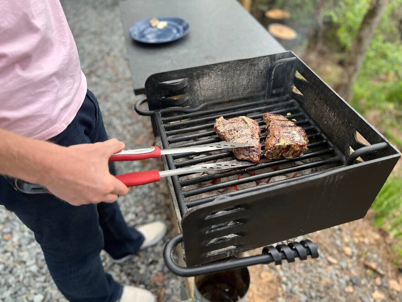 Une personne qui fait griller des steaks sur un barbecue extérieur.