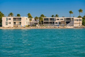 A beachfront hotel with multiple floors, balconies, and a pool area.