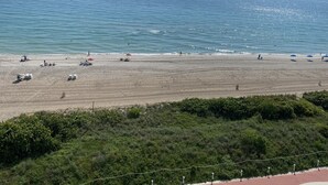 Una playa con un paseo marítimo empedrado y una vista despejada del océano.