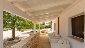 Un espace extérieur aménagé, abrité et doté de murs en pierre, d’une pergola et d’une vue sur un jardin.