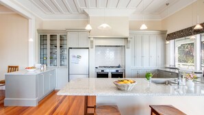 Een moderne keuken met een groot eiland, houten krukken en uitzicht op het groen buiten het raam.