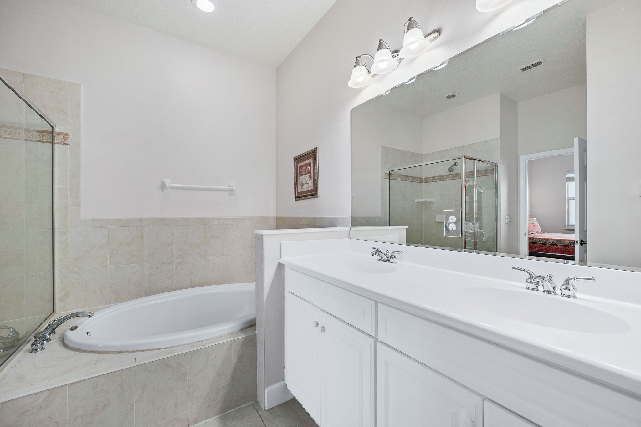 A modern bathroom with a large bathtub, a double sink vanity, and a walk-in shower.