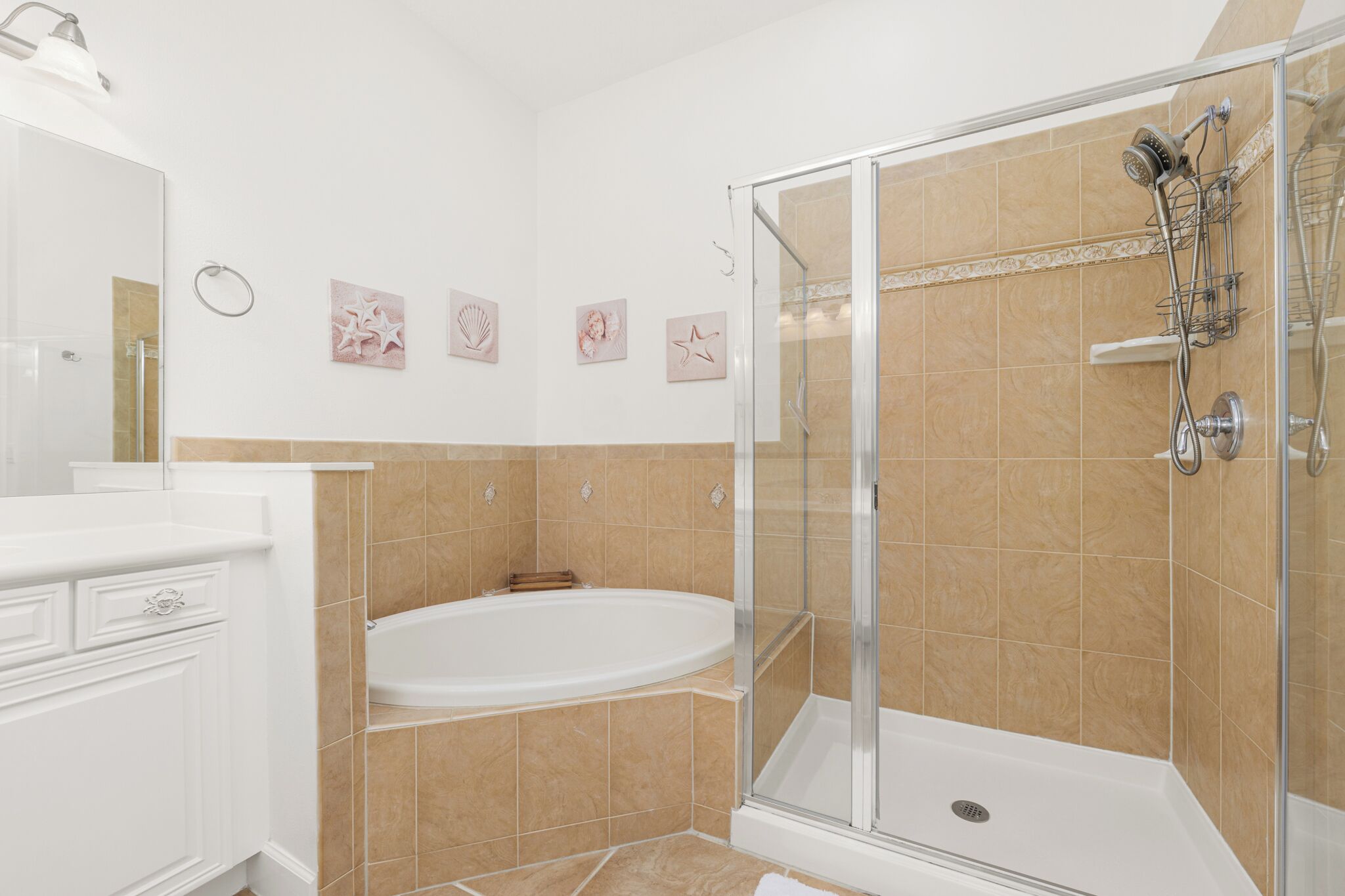 A modern bathroom with a glass-enclosed shower, a white bathtub, and beige tiles.
