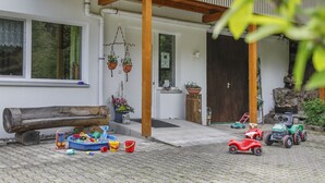 A house with a wooden porch, a log bench, and a variety of children's toys and vehicles on the ground. - Vacation apartment Sonnenblick (Zell am Harmersbach)