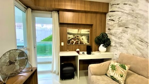 Un salon moderne avec un canapé, un bureau, un ventilateur et une vue sur un balcon.