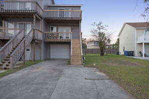 A two-story residential building with a front garage, a wooden staircase, and a small front yard.